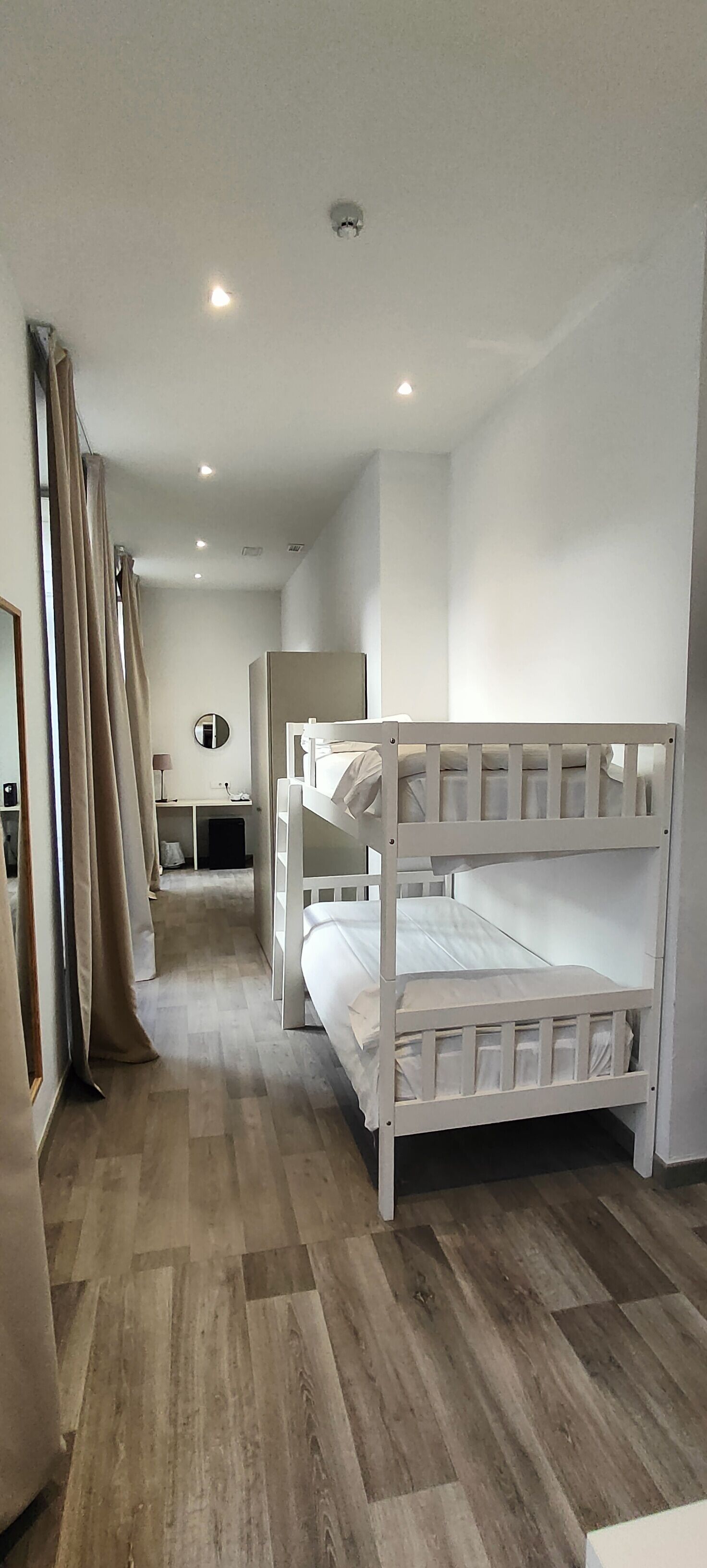 A bedroom with bunk beds, a desk, and a mirror.