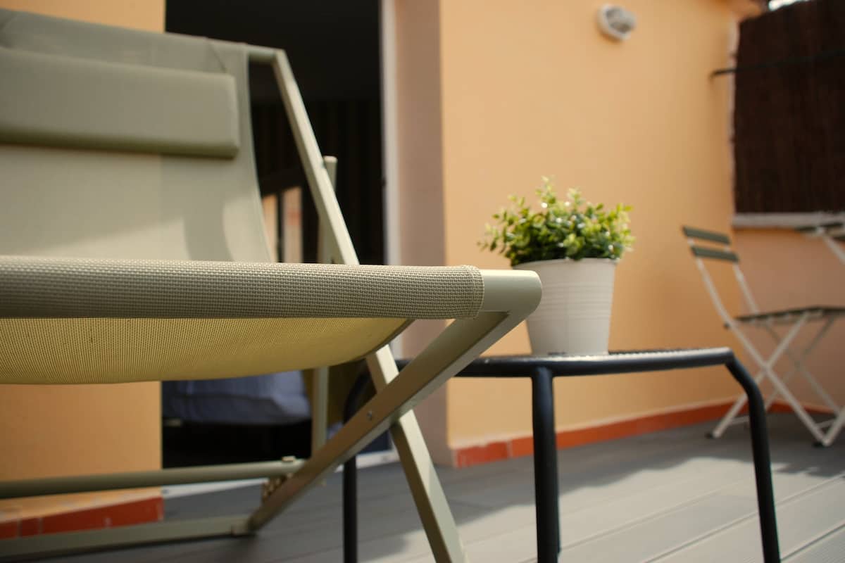 A balcony with a folding chair, a potted plant, and a folding table.