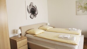 A double bed with two pillows, a bedside table with a lamp, and artwork on the wall. - rent-a-home Schweizergasse (Basel)