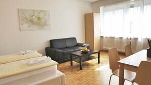 A modern living room with a sofa, a dining table, and a coffee table. - rent-a-home Schweizergasse (Basel)
