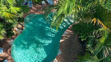 Una piscina al aire libre, sombrillas, sillones reclinables de piscina