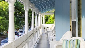 Un porche cubierto con columnas blancas y muebles de mimbre.