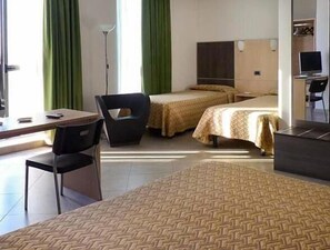 A hotel room with two beds, a desk, a chair, and a TV.