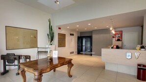 A reception area with a wooden reception desk, a large cactus plant, and a modern interior design. - Hotel Lux Modena (Modena)