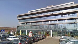 A multi-story hotel with a modern glass facade, a parking lot in front, and a sign for 'Hotel Lux'. - Hotel Lux Modena (Modena)