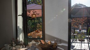 A dining area with a table set for tea, a basket of bread, and a view of an outdoor patio with umbrellas. - Villa Tresino Appartamenti B&B (Castellabate)