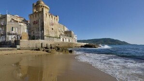 A coastal building with a tower, situated on a sandy beach with waves crashing nearby. - Villa Tresino Appartamenti B&B (Castellabate)