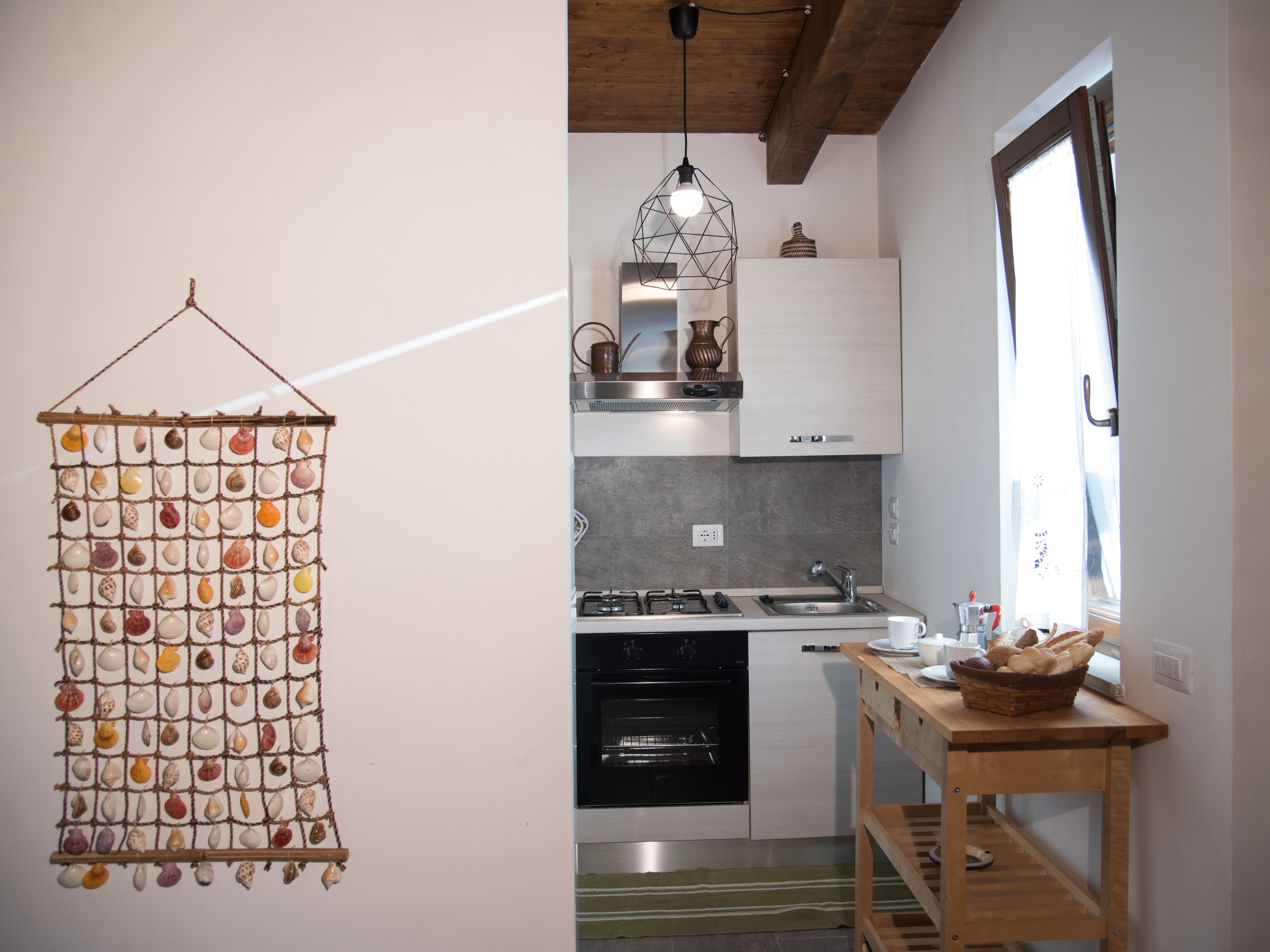 Una cocina con una decoración de concha colgante, estufa, fregadero y ventana con vistas.