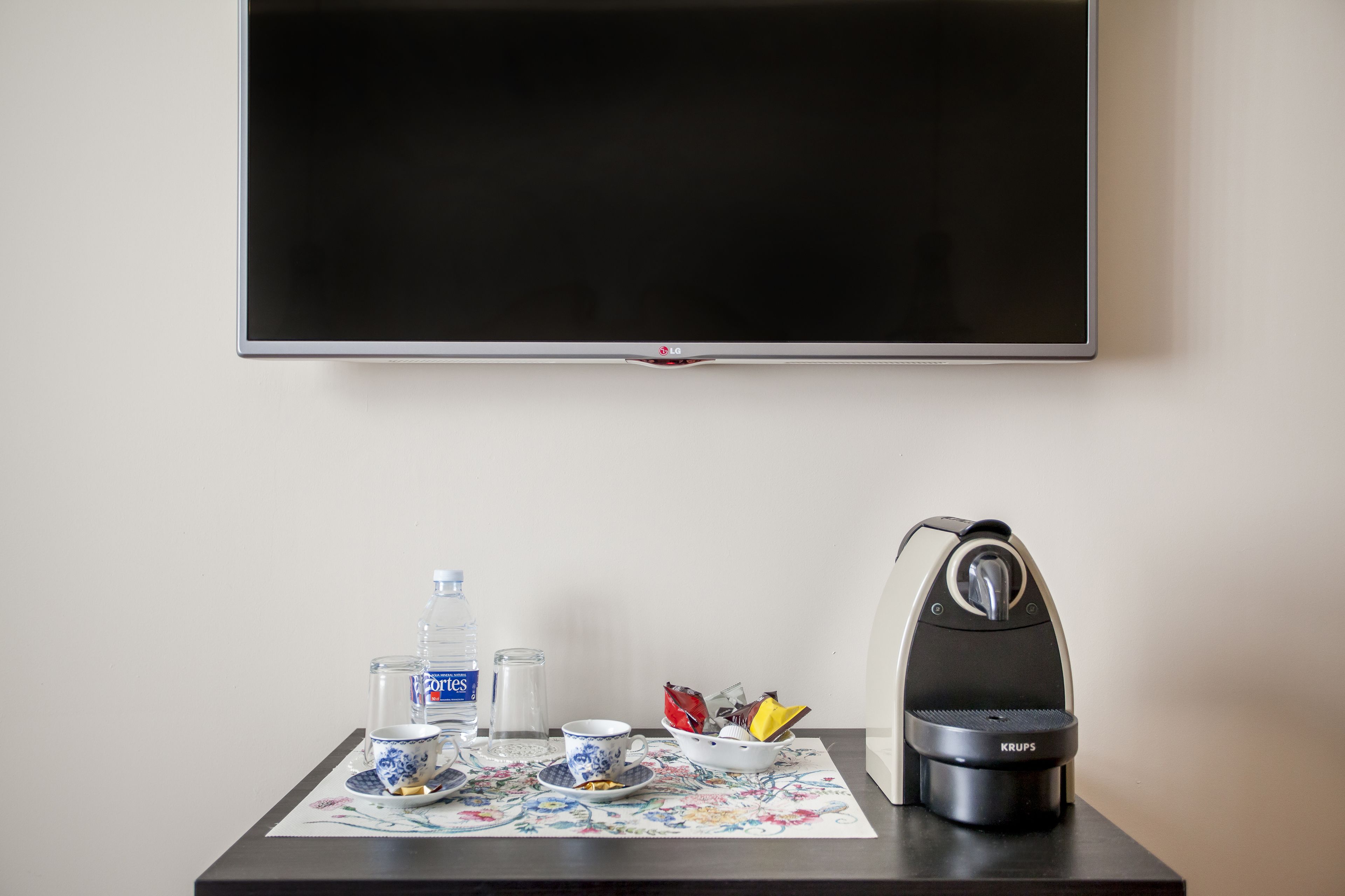 A table with a water bottle, a glass, a cup, a plate with food, and a Krups coffee maker.