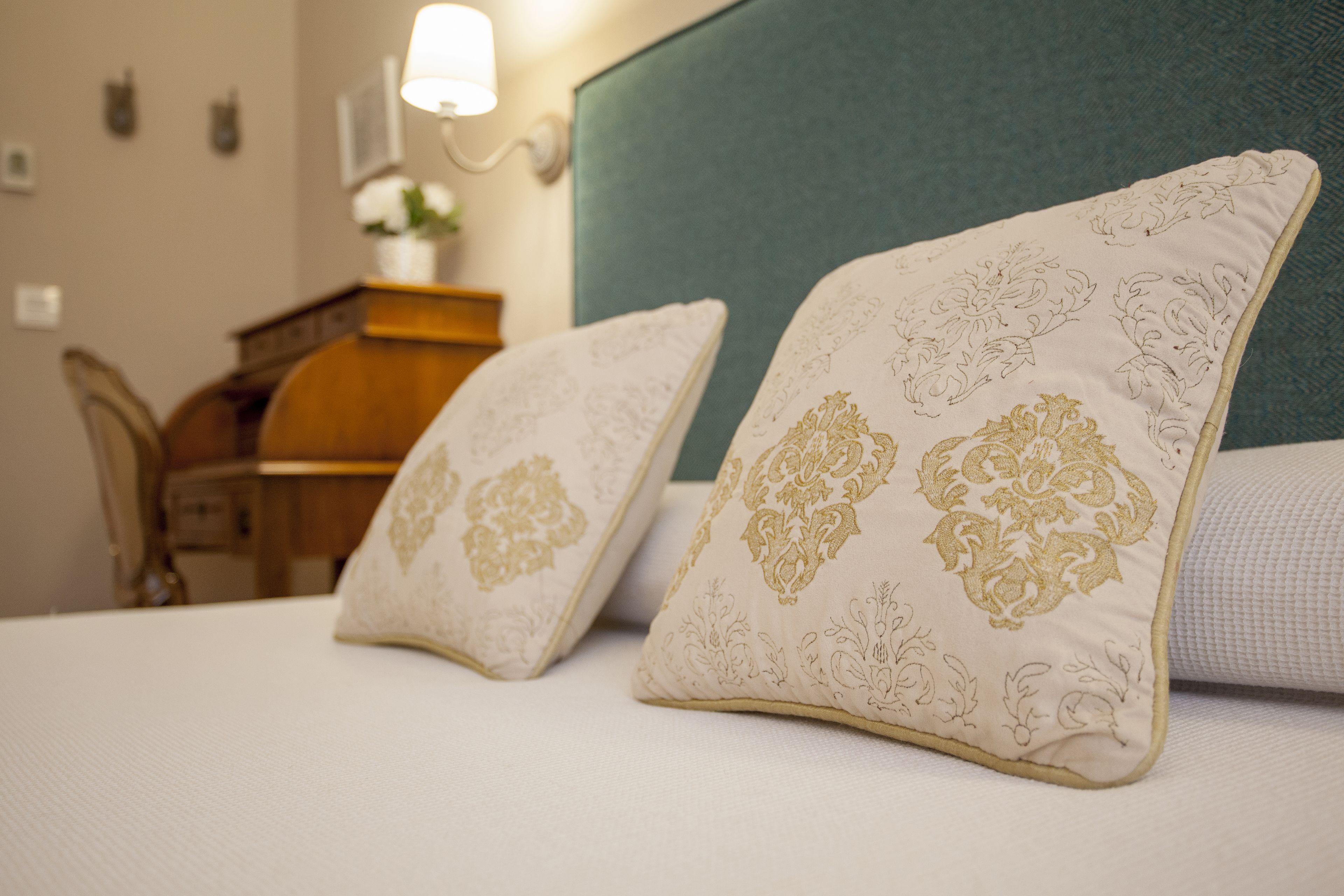 A neatly made bed with two decorative pillows and a headboard.