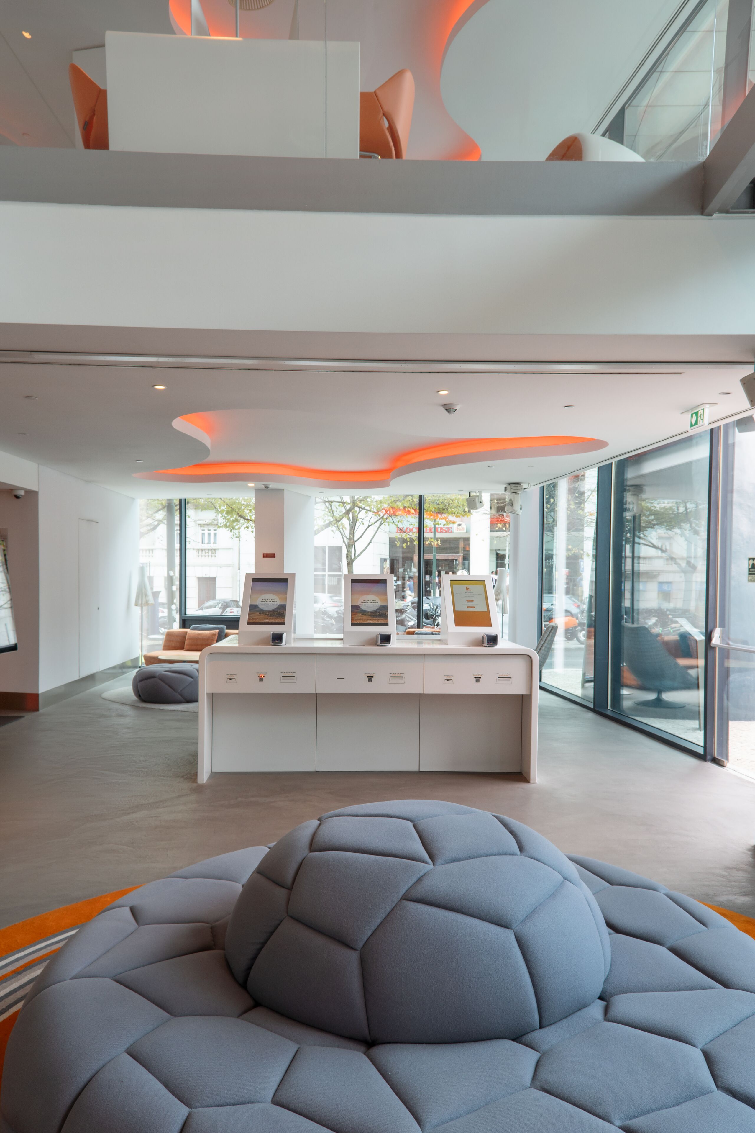 A modern reception area with a seating area, a reception desk, and a large window providing a view of the street.