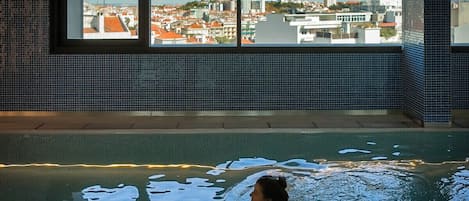 A pool with a view of a cityscape through large windows.