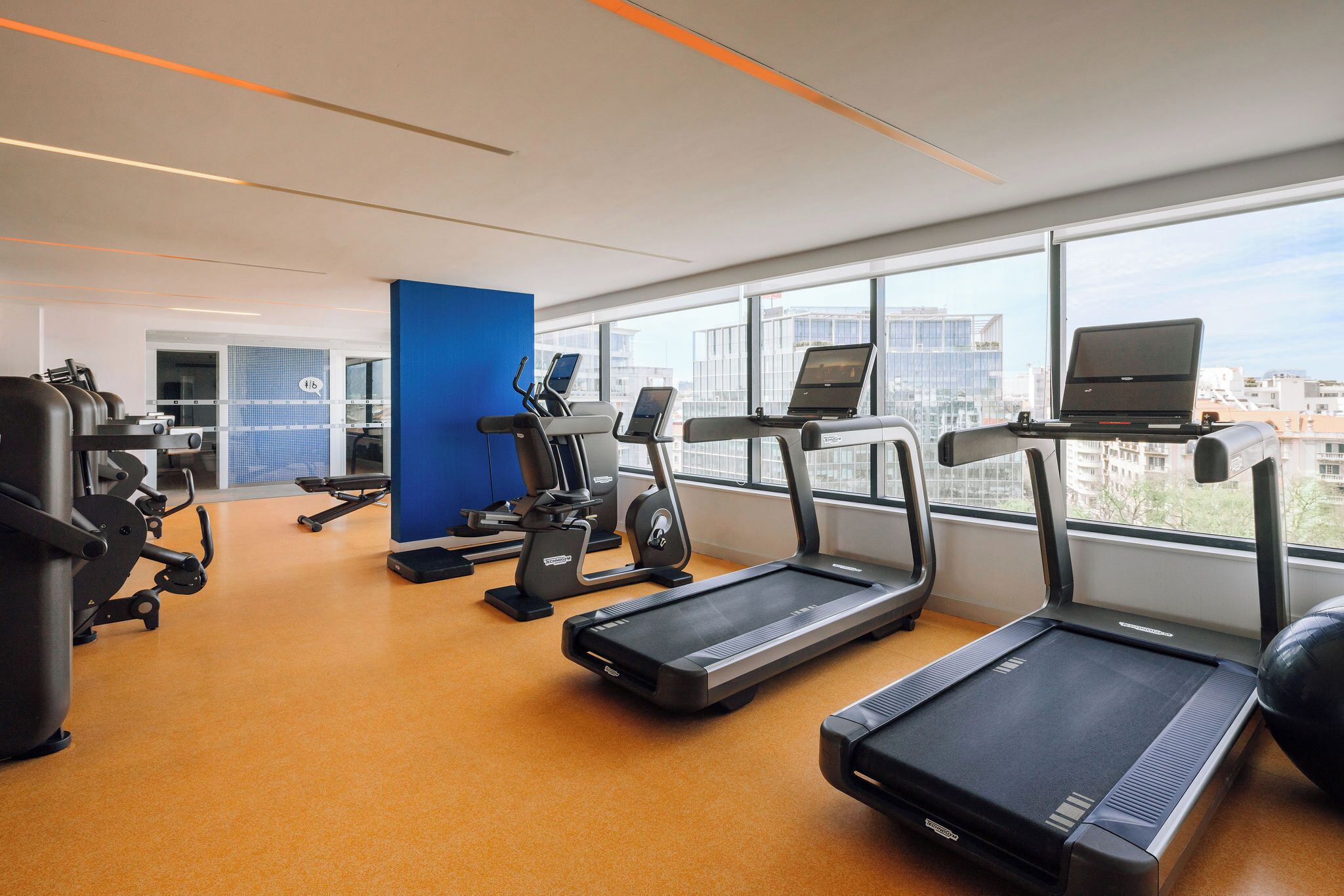 Un gimnasio con cintas de correr, elípticas y equipo de pesas.