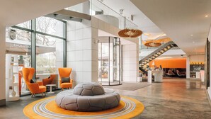 Un moderno vestíbulo de hotel con un amplio espacio de estar, una escalera y vistas al exterior.