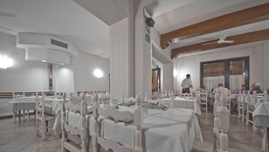 A dining area with white tables and chairs, a ceiling fan, and a visible exit sign. - Hotel Italia Ristorante Pizzeria (Reggello)