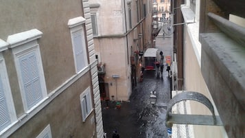 A narrow street with buildings on both sides, a person walking, and a parked bicycle.