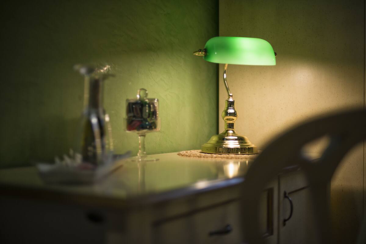 A desk with a lamp, a bottle, and a small decorative item.
