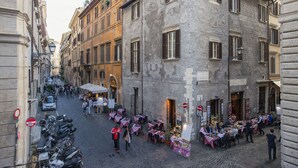 A cobblestone street lined with buildings, outdoor seating at cafes, and parked motorcycles. - Navona Tower Relais (Rome)