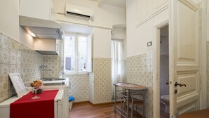 A compact kitchen with a red countertop, a sink, and a window. - Navona Tower Relais (Rome)