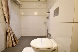 A small, clean bathroom with a toilet, shower, and towel rack.