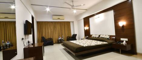 A modern hotel room with a bed, a desk, a chair, a TV, and a ceiling fan.