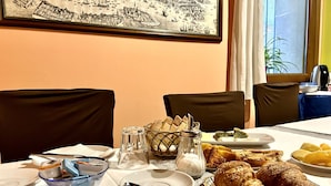 A breakfast table set with croissants, bread, and pastries, with a salt and pepper shaker, a bowl of fruit, and a plate of cheese. - Alloggi Serena (Venice)