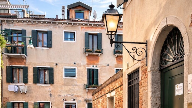 A narrow Venetian alley with stone paving, a canal, and traditional buildings with balconies and shutters. - Alloggi Serena (Venice)