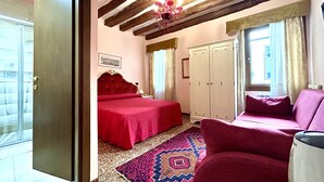 A bedroom with a bed, a sofa, a wardrobe, and a chandelier. - Alloggi Serena (Venice)
