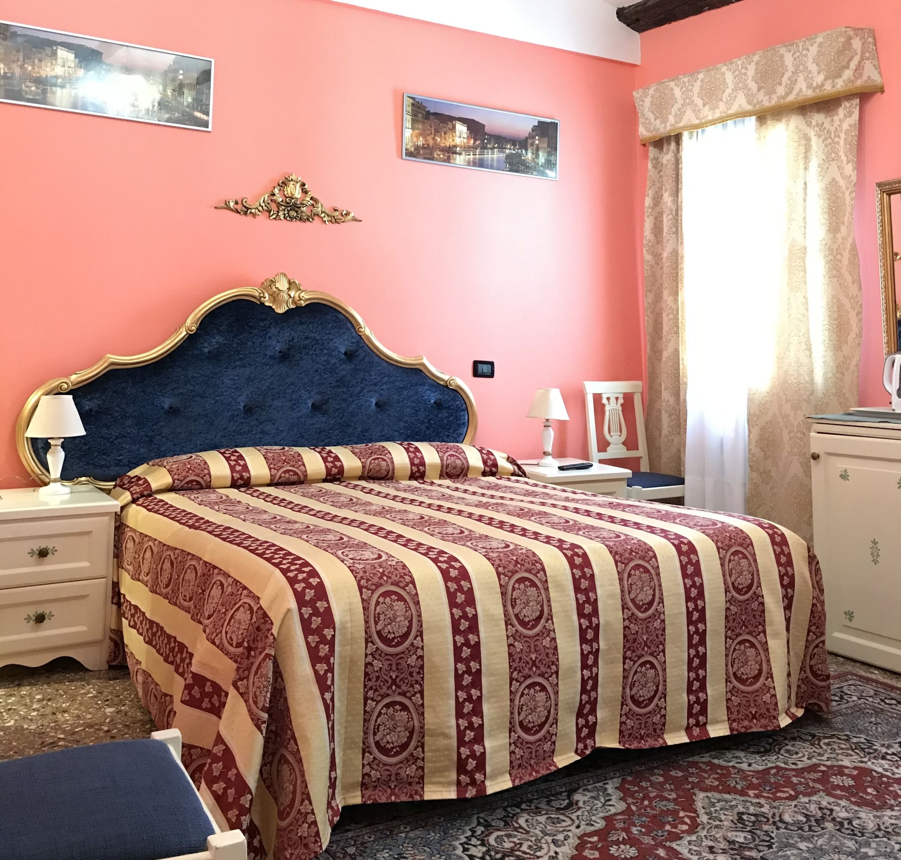 Un dormitorio con una cama grande, una mesita de noche, un aparador y una ventana con cortinas.