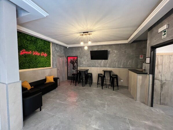 A modern lobby with a green wall, a black sofa, and a bar area with stools. - Palladini Rome (Rome)