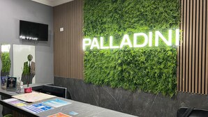 Un taulell de recepció amb un senyal 'PALLADINI', un televisor de pantalla plana i fulletons informatius.