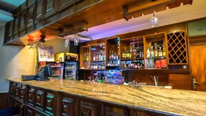 Eine Bar mit einer Marmorplatte, Holzkästen und Regalen voller Flaschen.
