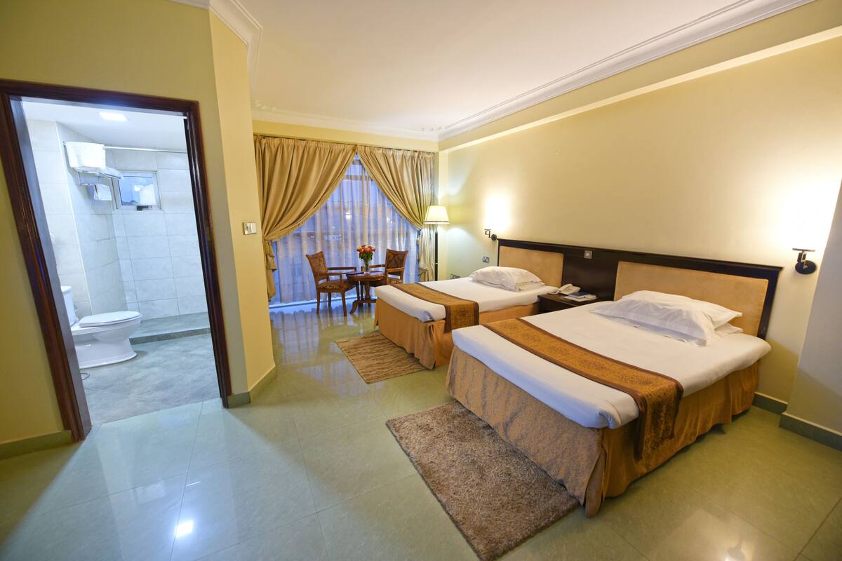 Ein Hotelzimmer mit zwei Betten, einem Badezimmer und einem Essbereich.