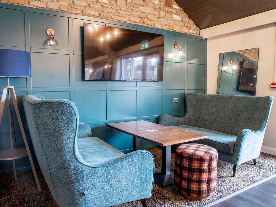Un área de estar moderna con asientos tapizados en color turquesa, una mesa de madera y un rug con estampado.