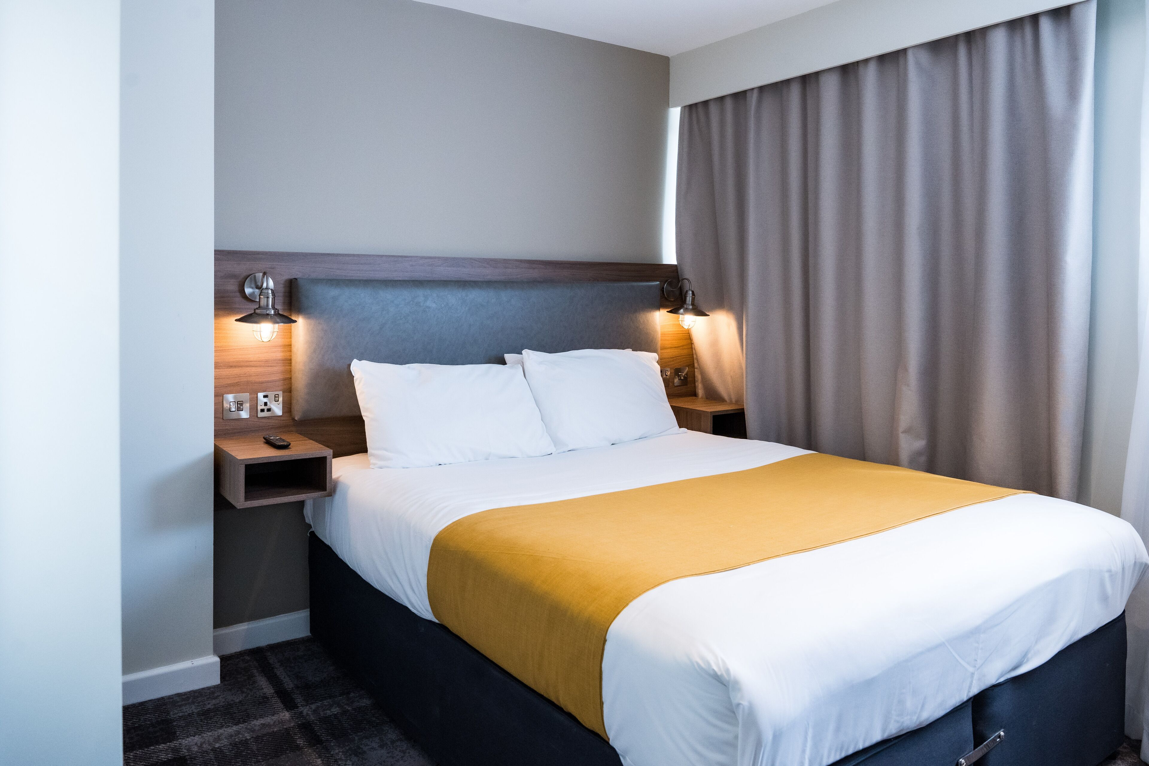 A hotel room with a large bed, two bedside tables, and a headboard.
