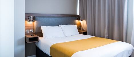 A hotel room with a large bed, two bedside tables, and a headboard.