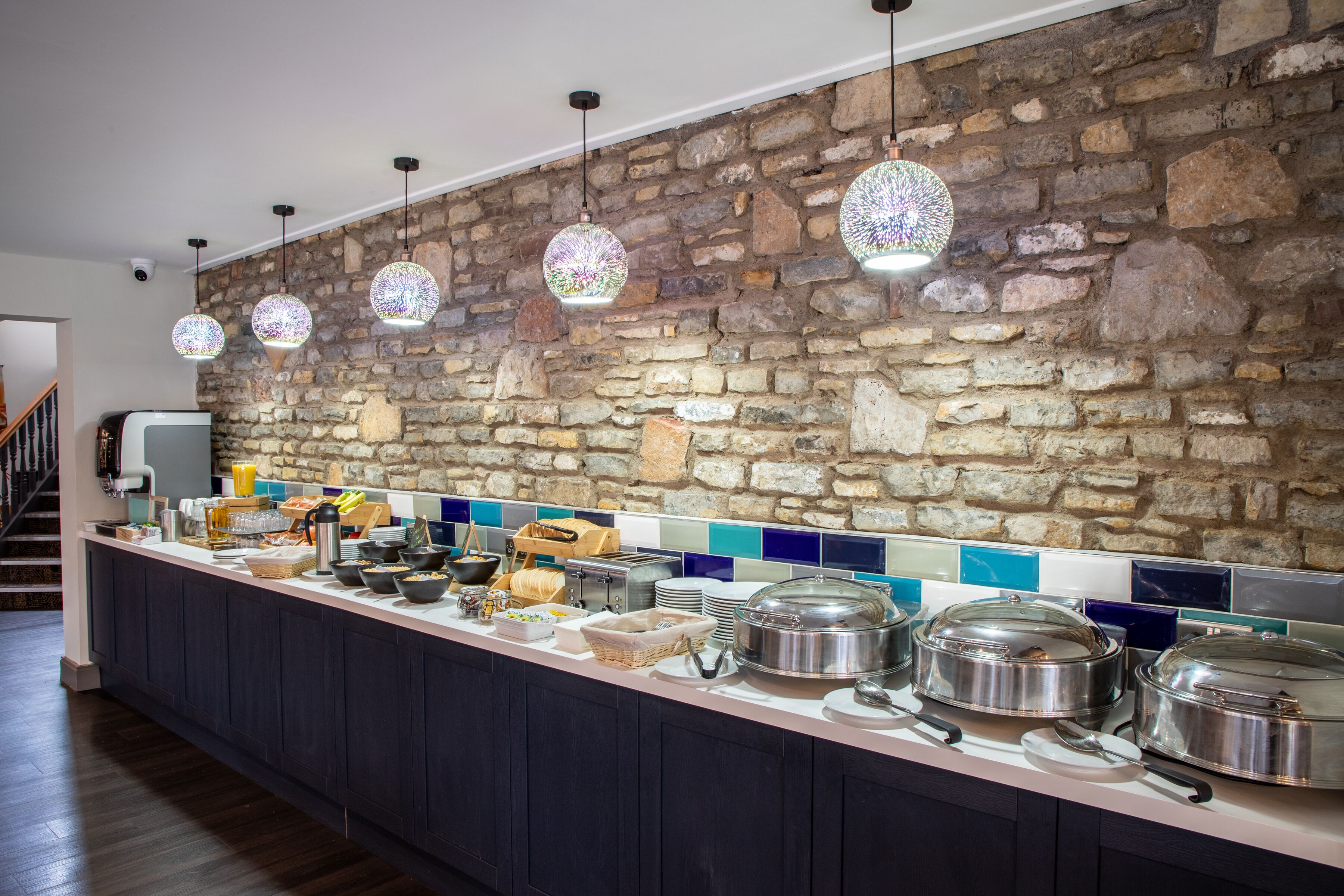 A breakfast bar with stone wall backdrop, hanging pendant lights, and buffet setup.