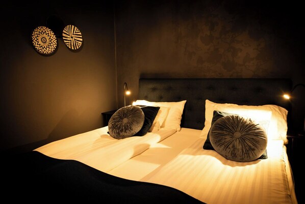 A neatly made bed with two pillows, a headboard, and two wall-mounted decorative items.