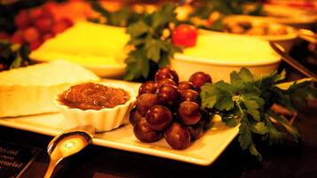 Une table garnie d’une variété d’aliments, notamment du fromage, des raisins et un bol de confiture.