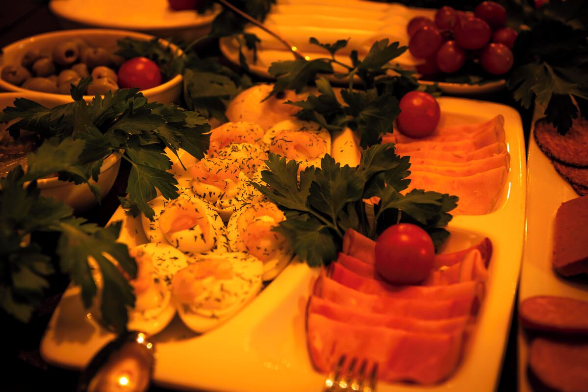 A table with various food items including sliced meat, olives, and tomatoes, garnished with parsley.