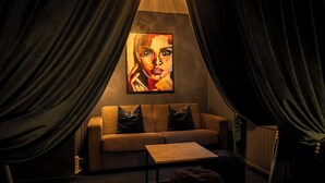 A cozy room with a sofa, a coffee table, and a painting on the wall. - Hotell Aqva Restaurang & Bar – Ett Biosfärhotell med fokus på hållbarhet (Mariestad)