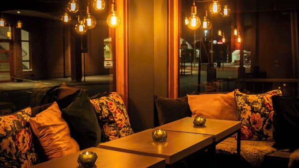 A cozy restaurant interior with wooden tables and floral-patterned cushions. - Hotell Aqva Restaurang & Bar – Ett Biosfärhotell med fokus på hållbarhet (Mariestad)