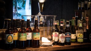 A bar with various bottles of alcohol, including beer and wine, and a large glass container. - Hotell Aqva Restaurang & Bar – Ett Biosfärhotell med fokus på hållbarhet (Mariestad)