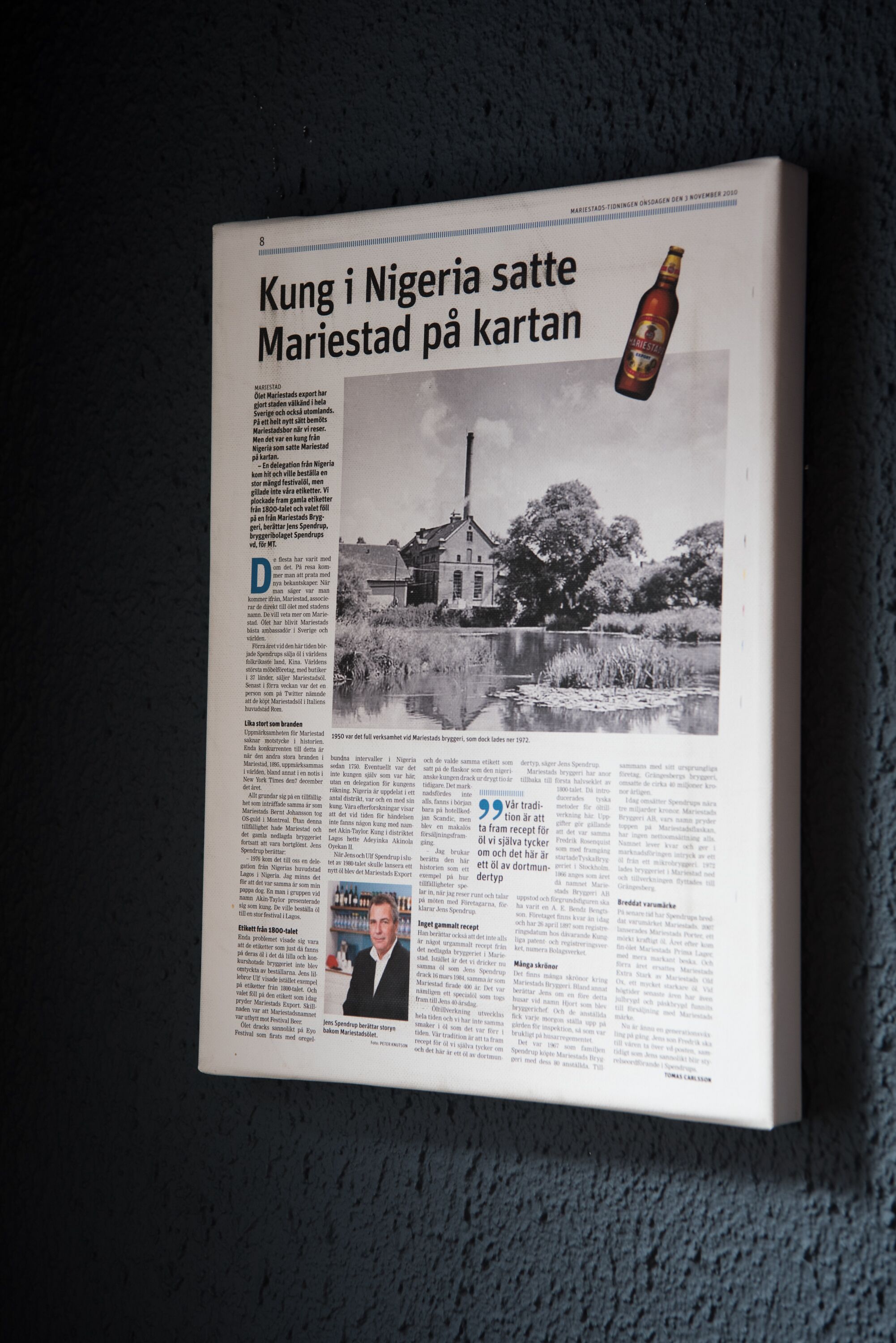 Un artículo de periódico titulado 'Kung i Nigeria satte Maristad på kartan' con una fotografía de un edificio y una botella de cerveza.
