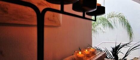 A cozy corner with a small table holding candles, a potted plant, and a view of the outdoors.