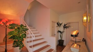 A staircase with white railings, a potted plant, and a table with candles. - Benali Guesthouse (Tarifa)