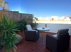 A patio with wicker furniture and potted plants. - Benali Guesthouse (Tarifa)