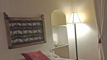 A bedroom with a bed, a nightstand, a lamp, and a wall-mounted artwork.