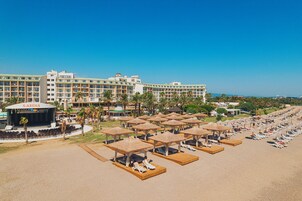 Un resort con múltiples sombrillas en la playa, sillones de sol y un escenario identificado como 'S-ARENA'.