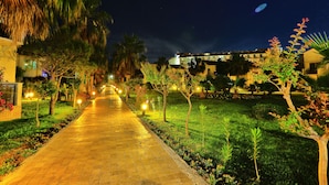 A nighttime pathway lined with trees and illuminated by street lamps, leading to a building with multiple balconies. - Selectum Family Comfort Side (Manavgat)